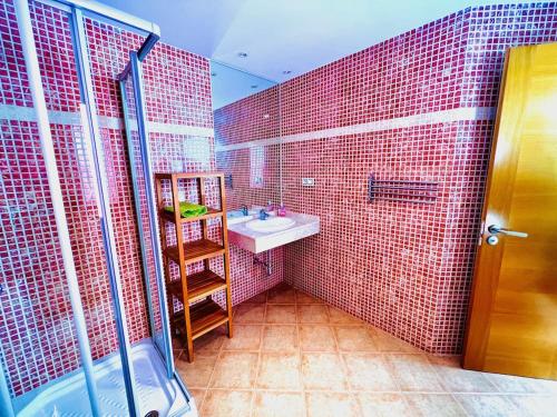 a bathroom with a sink and a red tiled wall at Villa Irina in Caleta De Fuste