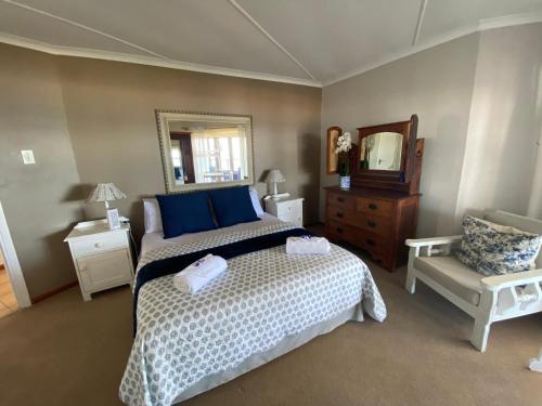 a bedroom with a bed and a mirror and a chair at Pienaars Guesthouse in Groot Brak Rivier