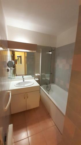 une salle de bain avec un lavabo et une baignoire dans l'établissement RIVAGES DE ROCHELONGUE Joli T2 piscine vue mer Rochelongue Cap d'Agde, au Cap d'Agde