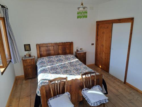 a bedroom with a bed and two chairs at L' antica Casa di Maria Lilia in Pieve di Cadore
