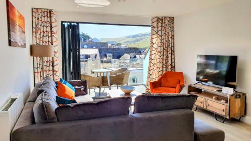 a living room with a couch and a television at 11 Putsborough - Luxury Apartment at Byron Woolacombe, only 4 minute walk to Woolacombe Beach! in Woolacombe