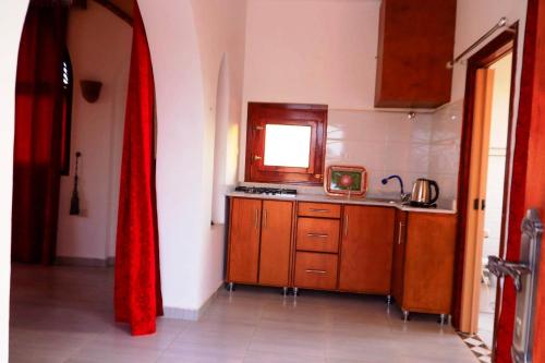 a kitchen with wooden cabinets and a red curtain at Thebes Hotel in Luxor