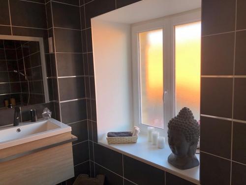 a bathroom with a window and a statue next to a sink at L'escapade champenoise in Villers-Marmery