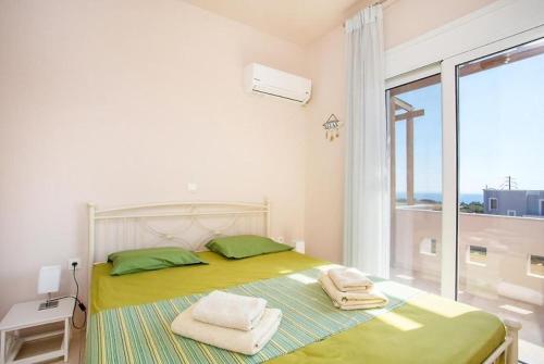 um quarto com uma cama com almofadas verdes e uma janela em Regina Villa - Family Dream with double pool em Lakhania