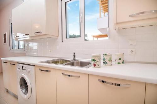 uma cozinha branca com um lavatório e uma máquina de lavar louça em Regina Villa - Family Dream with double pool em Lakhania