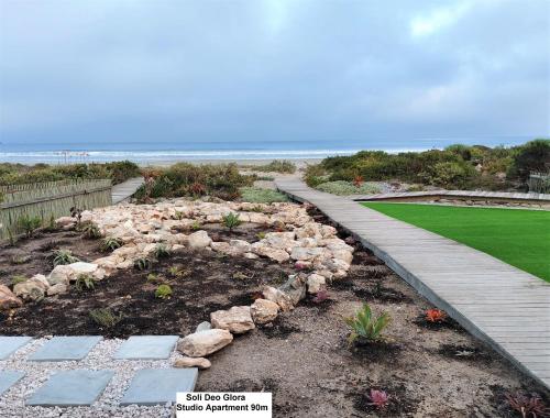 a garden with a pathway leading to the beach at Soli Deo Gloria, Pearl Studio in Paternoster