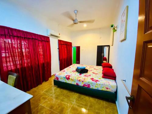 a bedroom with a bed with red drapes at NABILA HOMESTAY in Pantai Cenang