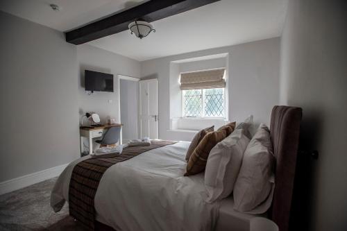 sypialnia z łóżkiem z białą pościelą i poduszkami w obiekcie The Berwyn Arms w mieście Corwen