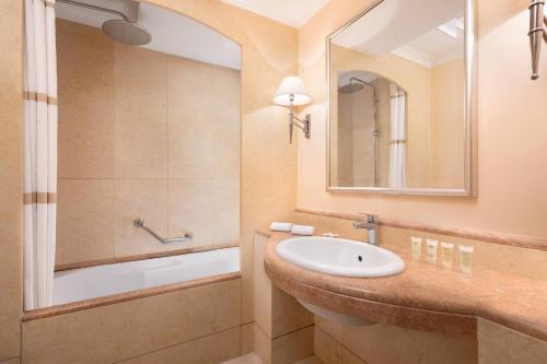 a bathroom with a sink and a tub and a mirror at Courtyard by Marriott Rome Central Park in Rome