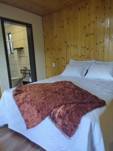 a large bed with a brown blanket on it at Recosta Chalés in Cambara do Sul