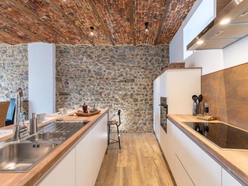 cocina con armarios blancos y pared de piedra en Spacious holiday home in Doische with private pool, en Doische