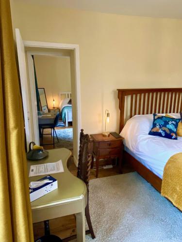 a bedroom with a bed and a table and a mirror at Le Portanel in Eymet