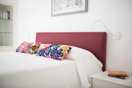 a white bed with a red headboard and two pillows at Casa Fernanda in Monopoli