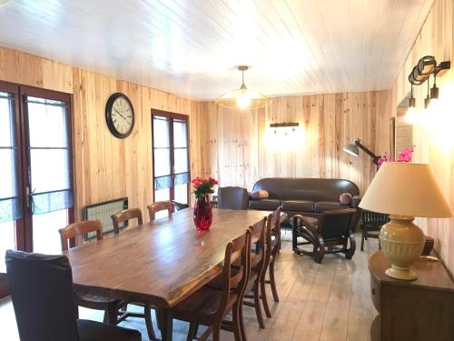 une salle à manger avec une table, des chaises et une horloge dans l'établissement Gîte de la Bécassière - Les cabanes océanes Montalivet, à Vendays-Montalivet