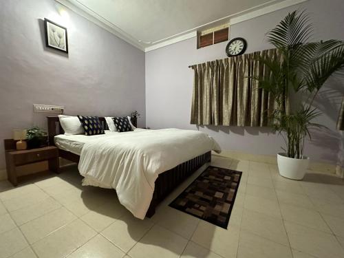 a bedroom with a large bed and a clock on the wall at Rustic Village Farmhouse in Bangalore