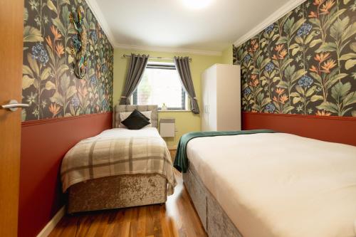 two beds in a small room with floral wallpaper at Ground Floor 2 Bedroom Apartment w Parking Sleep up to 6 in L3 in Liverpool