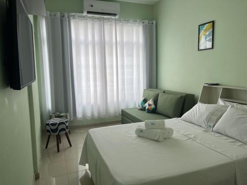 1 dormitorio con 1 cama blanca grande y 1 sofá en Studio com linda vista para a praia de Copacabana!, en Río de Janeiro