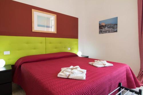 Casa Vacanze Belvedere في شيكلي: غرفة نوم بسرير احمر وعليها منشفتين