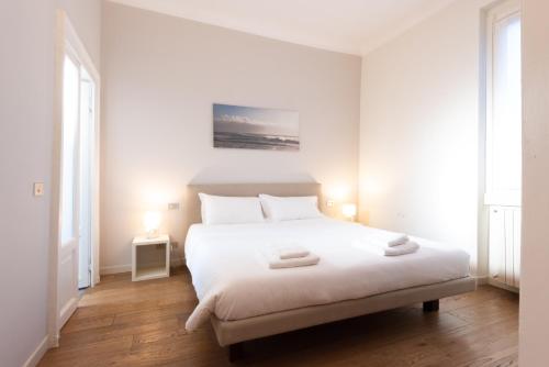a white bedroom with a white bed and two lamps at Porta Venezia Elegant Penthouse with Terrace in Milan