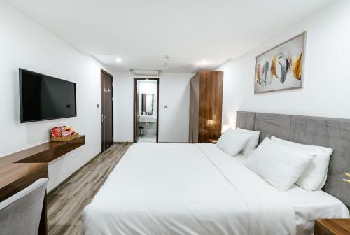 a bedroom with a white bed and a flat screen tv at SWEDEN HOTEL and APARTMENT in Da Nang
