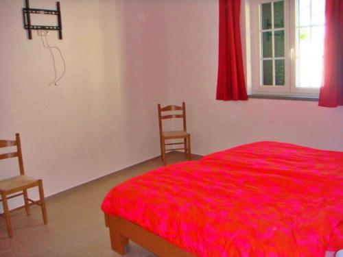 a bedroom with a red bed and two chairs at 4 Persoons Woning met Zwembad. Rustig gelegen. in Figueira e Barros