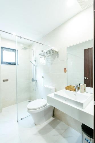 a white bathroom with a toilet and a sink at SWEDEN HOTEL and APARTMENT in Da Nang