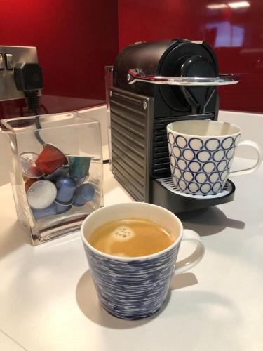 a cup of coffee sitting next to a toaster at Stylish Sea View Apartment with Parking in Penzance