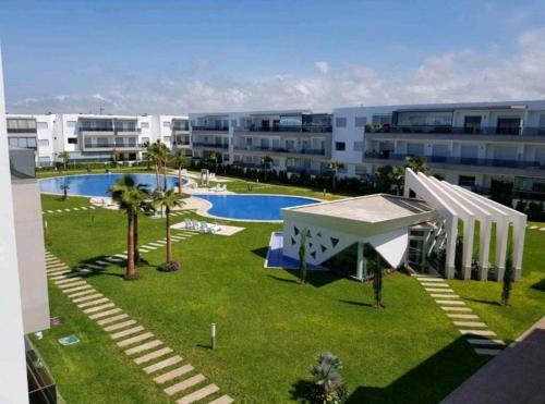 an apartment complex with a swimming pool and palm trees at Grand Apartement a Blanca Beach Sidi Rehal in Sidi Rahal