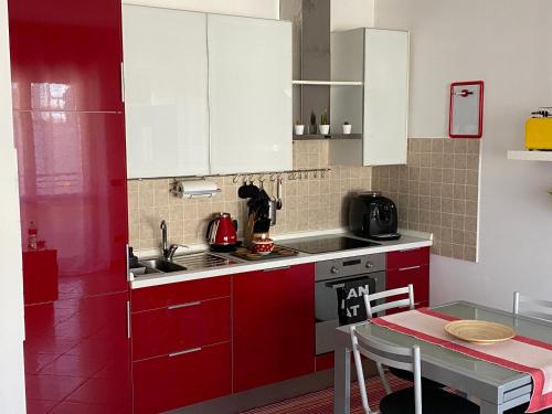 a red kitchen with white cabinets and a table at FIERA MILANO-RHO APARTMENT in Pero