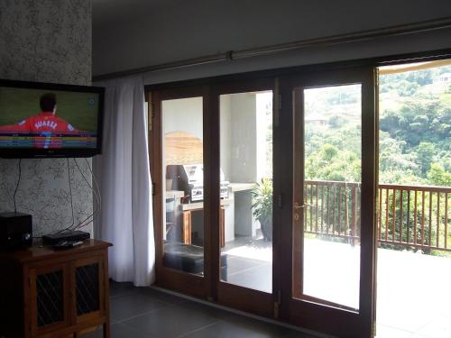 a living room with sliding glass doors and a television at Nkutu River Lodge in Kloof