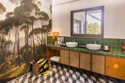 a bathroom with two sinks and a green tile wall at Villa Kulintang in Donsol