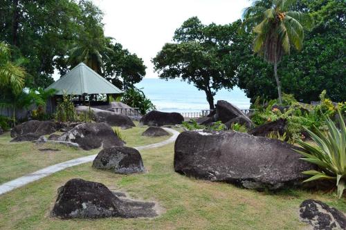 a garden with rocks and the ocean in the background at Riva D Etruschi Seychelles in Bel Ombre