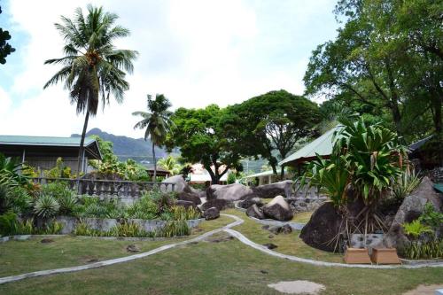 einen Garten mit Felsen und Bäumen und ein Haus in der Unterkunft Riva D Etruschi Seychelles in Bel Ombre