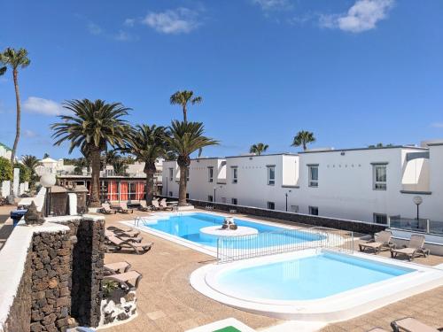 - Vistas a la piscina del complejo, con palmeras en Naia House Lanzarote en Puerto del Carmen