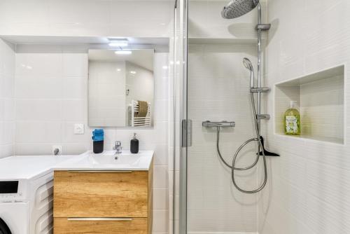 La salle de bains blanche est pourvue d'une douche et d'un lavabo. dans l'établissement Les Clés de Laure - Le 11 JACUZZI avec Terrasses Clim Netflix Parking, à Carcassonne
