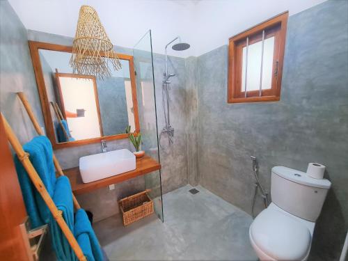 a bathroom with a shower and a toilet and a sink at Ohana Surf Guest House in Ahangama