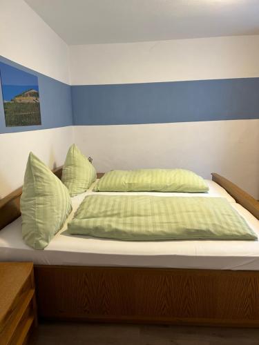 ein Bett mit grüner Bettwäsche und Kissen darauf in der Unterkunft Bed and Breakfast - Rheingauer Hof in Oestrich-Winkel