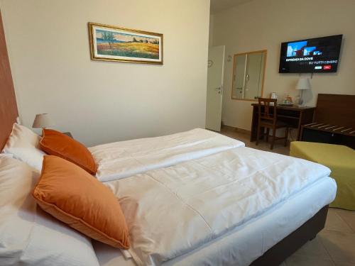 a bedroom with a bed with white sheets and orange pillows at Betty's House in Lazise