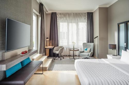 a hotel room with a bed and a flat screen tv at Le Méridien Hamburg in Hamburg