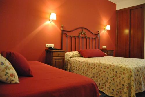 a hotel room with two beds with red walls at Hotel Amandi in O Grove