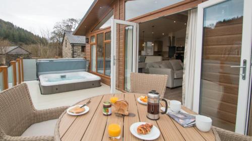 a wooden table on a patio with a hot tub at Llyn Padarn Lodge in Betws-y-coed