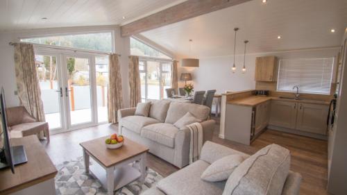 a living room with two couches and a kitchen at Llyn Padarn Lodge in Betws-y-coed