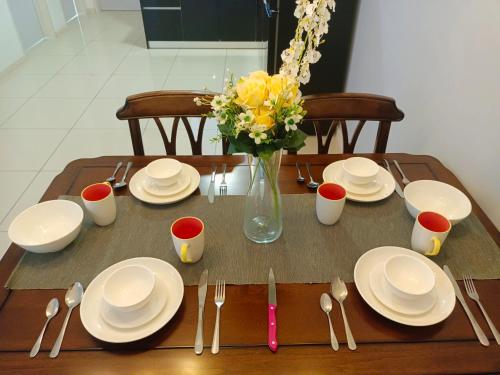 a table with white plates and a vase of flowers at Medini Elysia Park , 3 min to Legoland, Netflix By Hint Homestay in Nusajaya