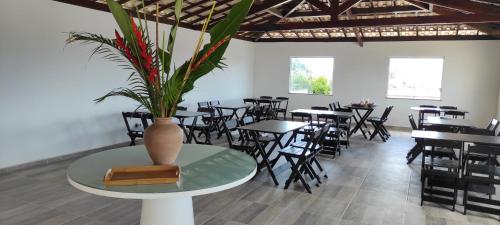 Pousada Jardins - Mar Grande في فيرا كروز دو إيتاباريكا: مطعم بطاولات وكراسي ومزهرية على طاولة