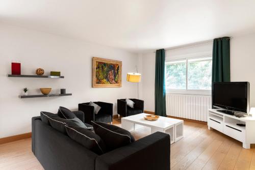 a living room with a black couch and a tv at Appartement Aloa in Carcassonne