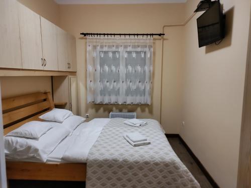 een kleine slaapkamer met een bed en een televisie bij Damjanich apartman in Kaposvár