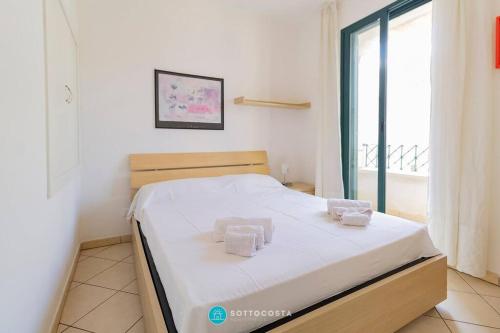 une chambre avec un lit avec des draps blancs et une fenêtre dans l'établissement CENTRAL SQUARE - San Foca, à San Foca