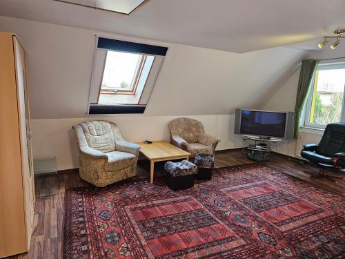 a living room with chairs and a tv and a rug at Carpe Diem in Grzybowo