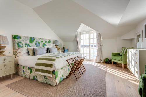 a bedroom with a large bed and a green chair at The Idle Rocks in Saint Mawes
