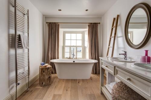 a bathroom with a tub and two sinks and a mirror at The Idle Rocks in Saint Mawes